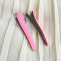 Pink and black hair clips on a white fabric background