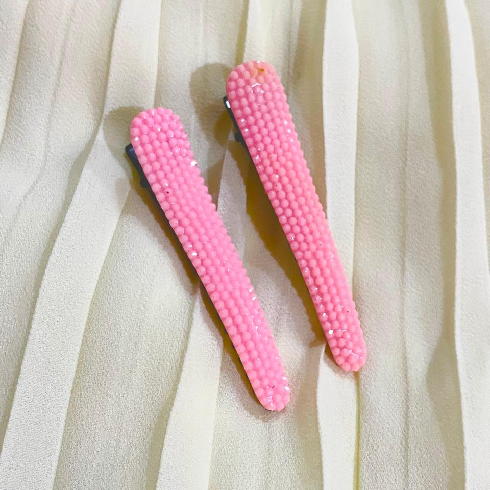 Two pink hair clips on a white fabric background