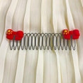 Hair comb with red floral attachments on a white curtain background
