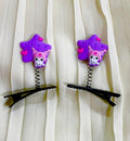 Two purple star-shaped hair clips with pink octopus designs on a white curtain background.