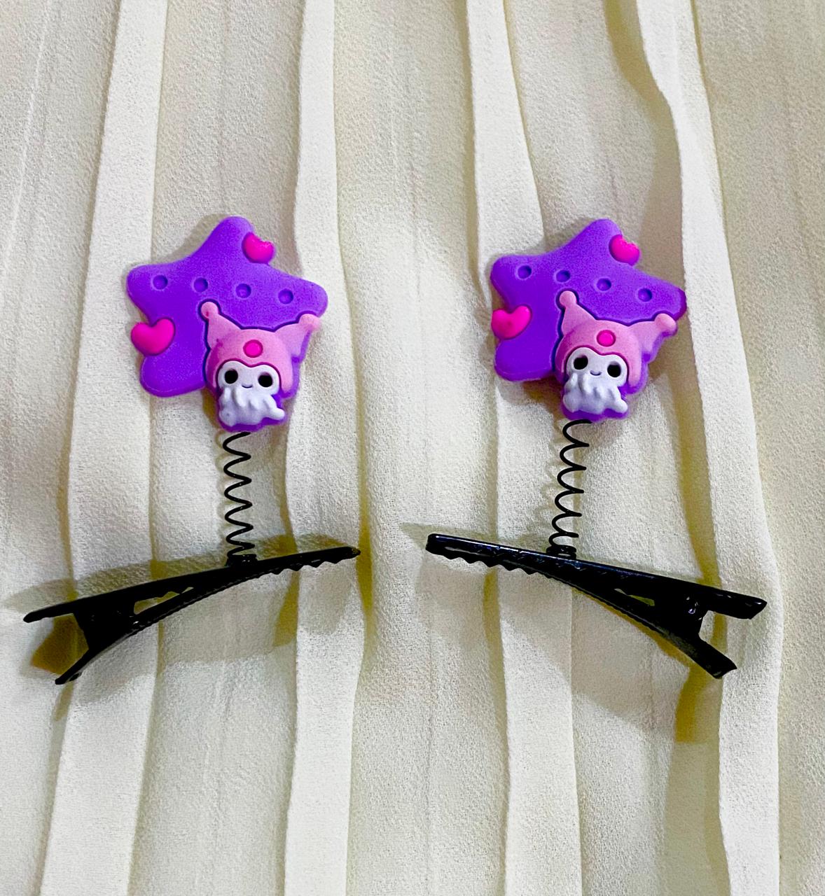 Two purple star-shaped hair clips with pink octopus designs on a white curtain background.