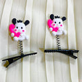 Two cartoon-style hair clips with heart shapes on a white curtain background