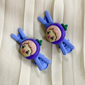 Two cartoon character hair clips on a white fabric background