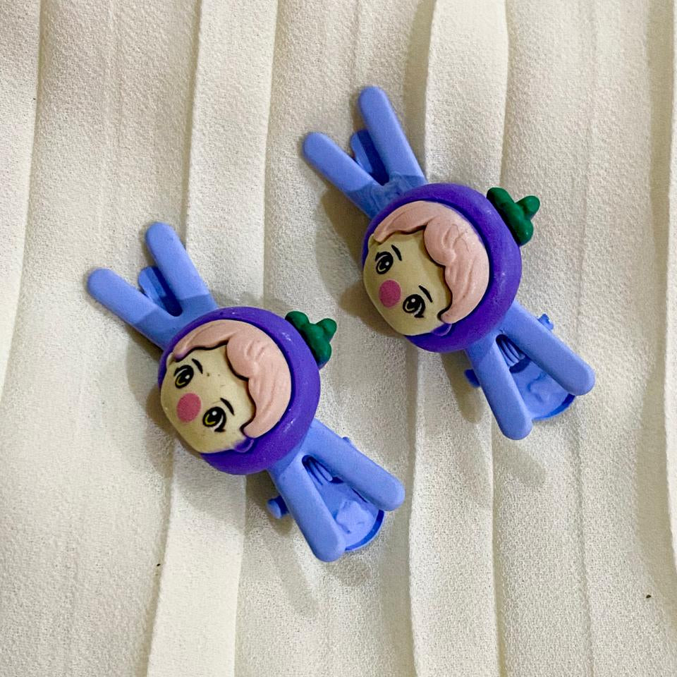 Two cartoon character hair clips on a white fabric background
