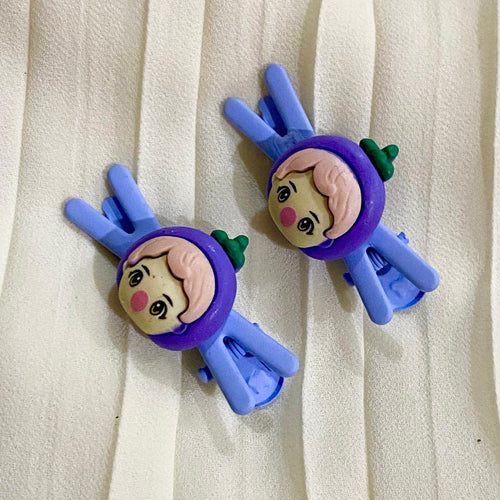 Two cartoon character hair clips on a white fabric background