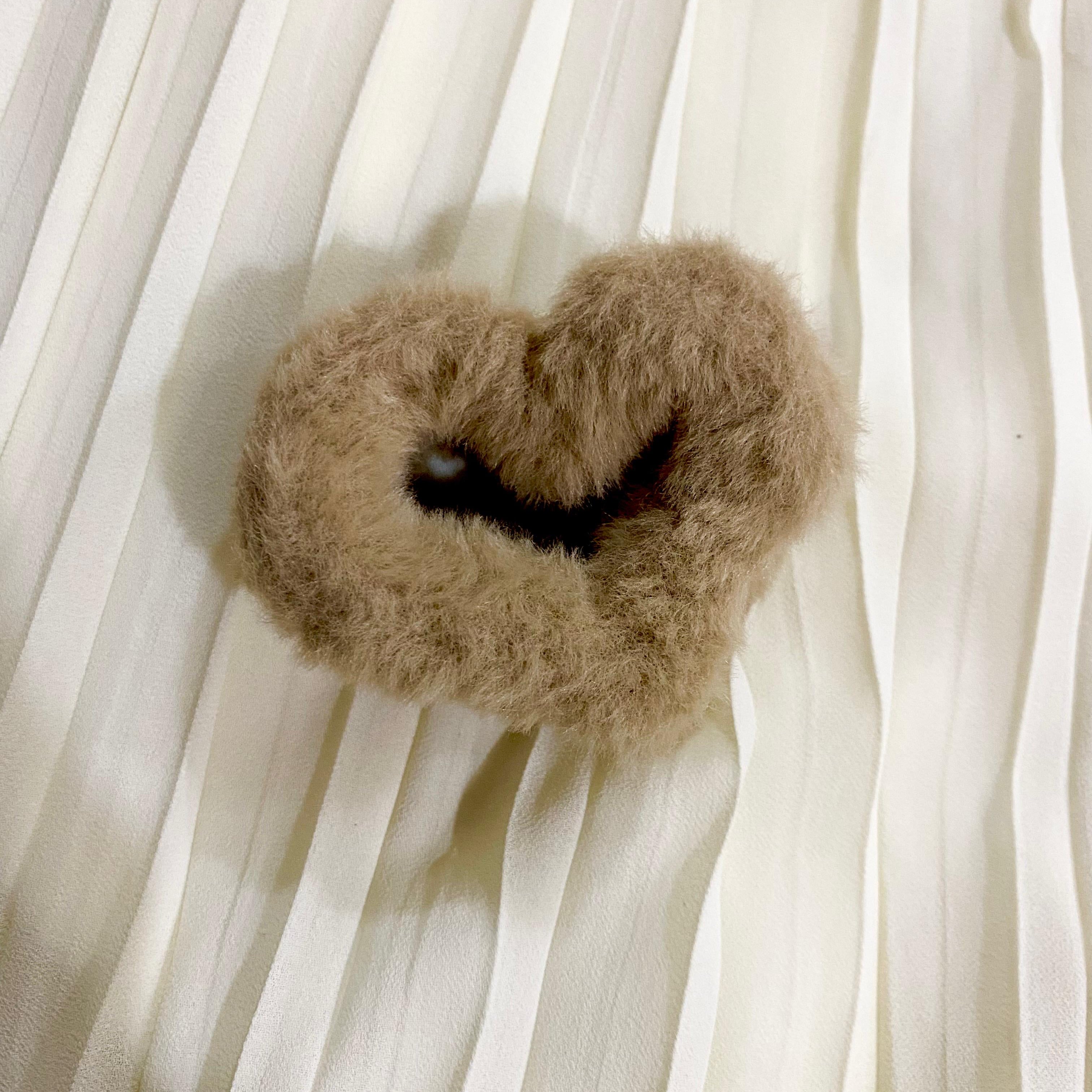 Heart-shaped brown pillow with a black center on a white fabric background