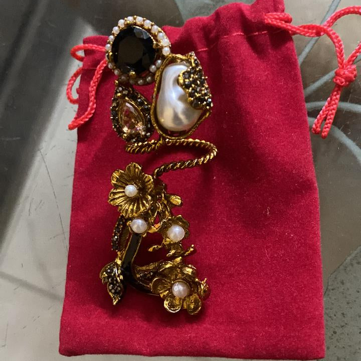 Decorative brooch with pearls on a red fabric pouch