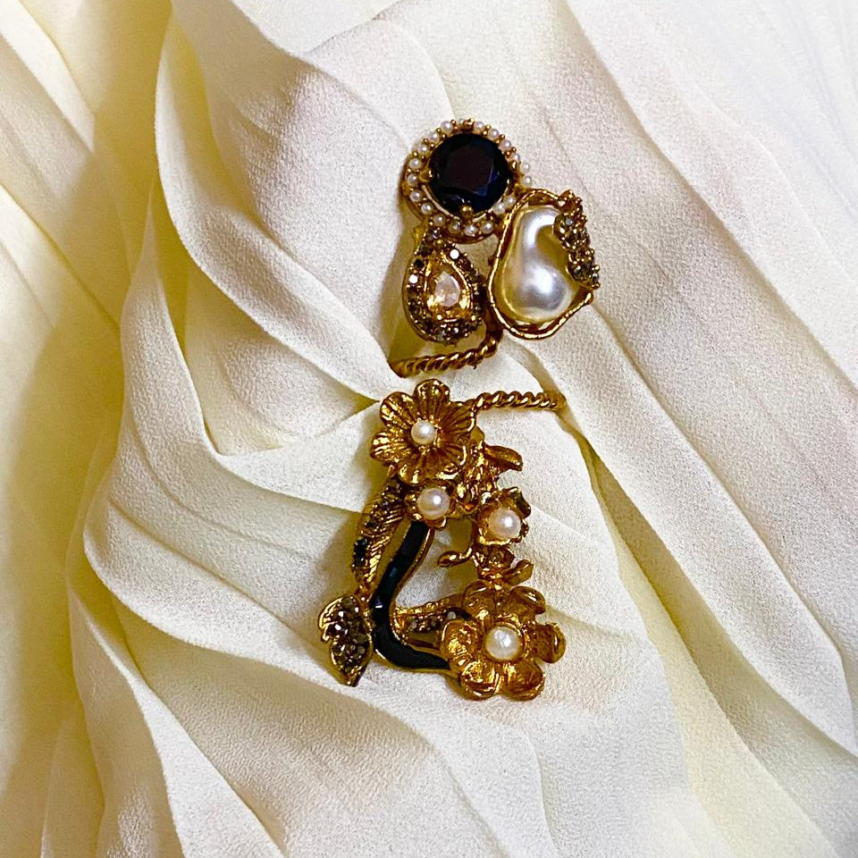 Gold brooch with pearls and a central gemstone on white fabric