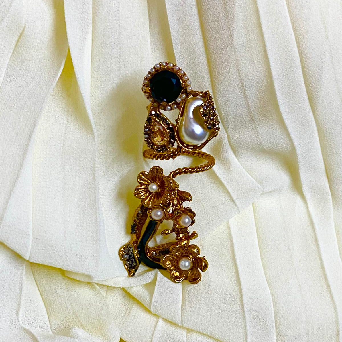 Ornate earring with gemstones on a white fabric background