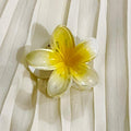 Yellow flower-shaped hair clip on a white fabric background