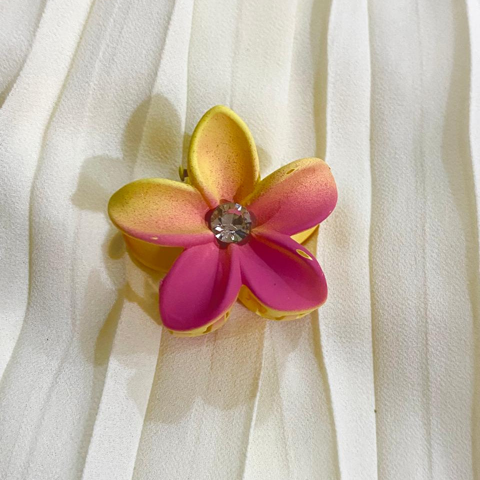 Flower-shaped brooch with pink and yellow petals on a white fabric background