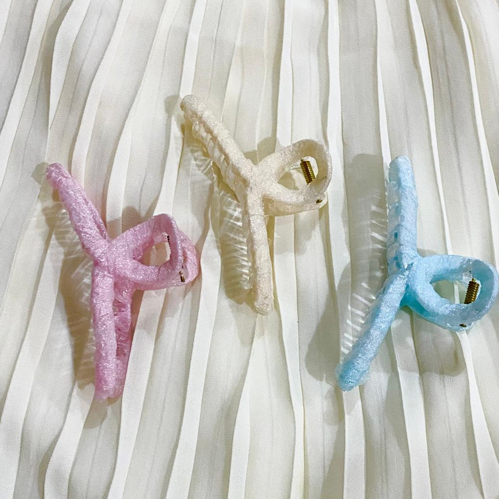 Three colorful hair clips on a white fabric background