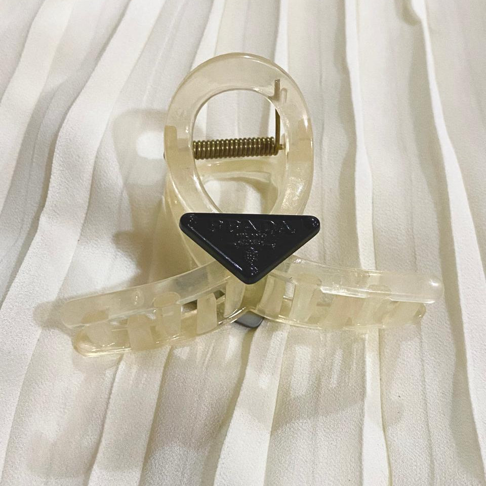 Clear plastic clip with a black triangular component on a white fabric background