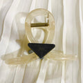 Clear plastic clip with a black triangular component on a white fabric background