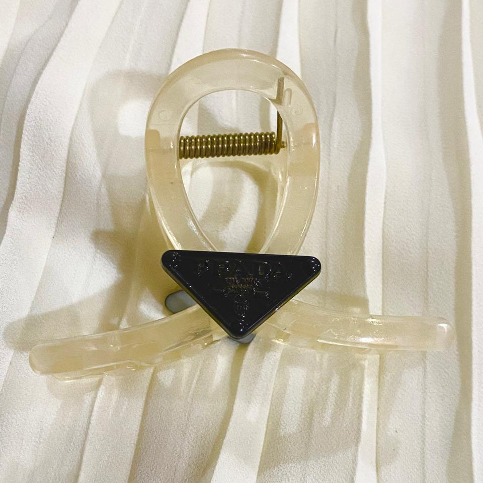 Clear plastic clip with a black triangular component on a white fabric background