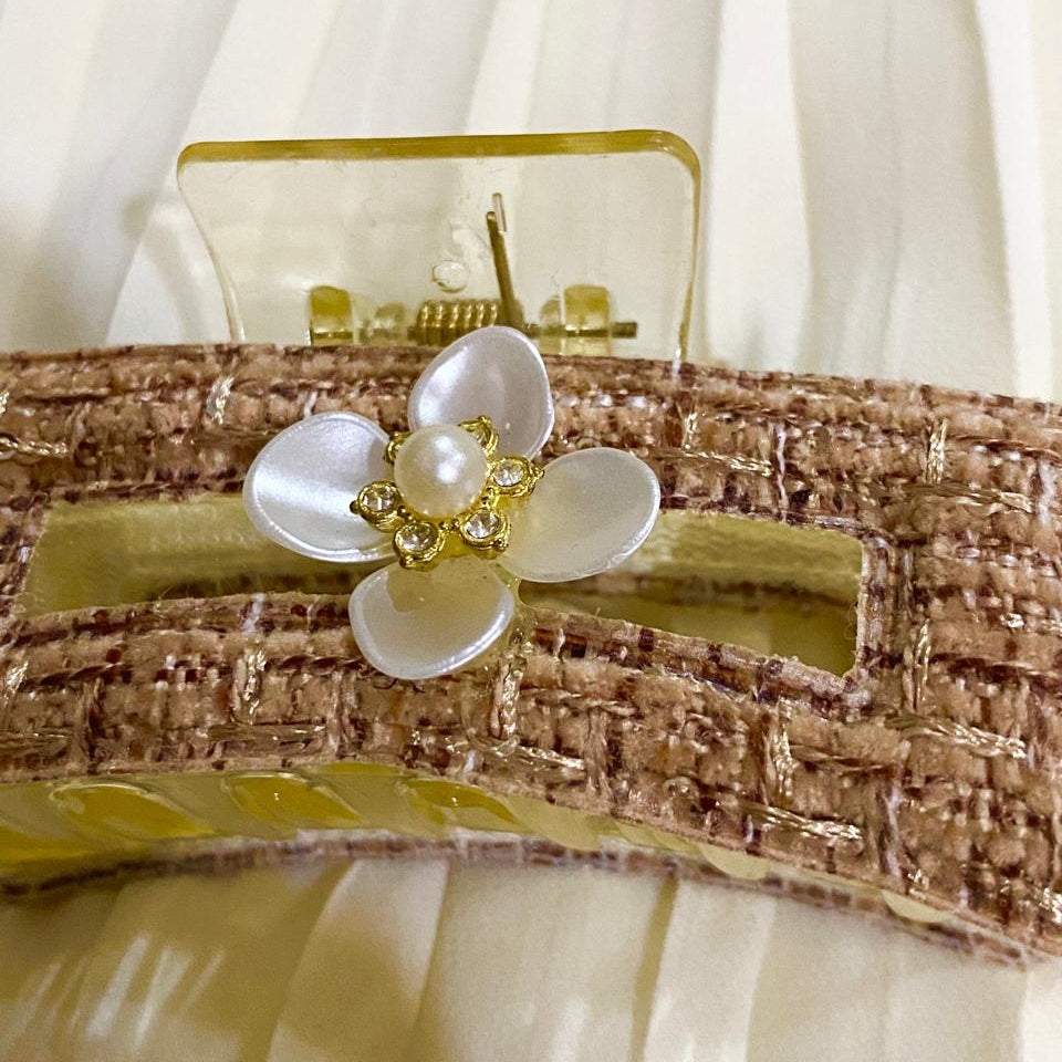 Decorative headband with a white flower and pearl-like center on a white background