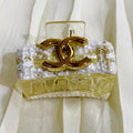 Gold Chanel brooch on a white fabric background