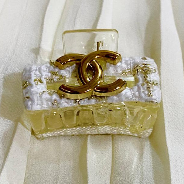 Gold Chanel brooch on a white fabric background