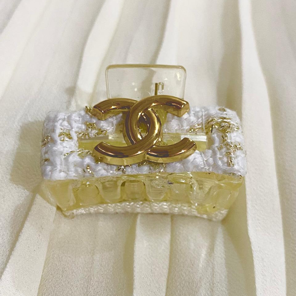 Chanel perfume bottle with gold cap on a white fabric background