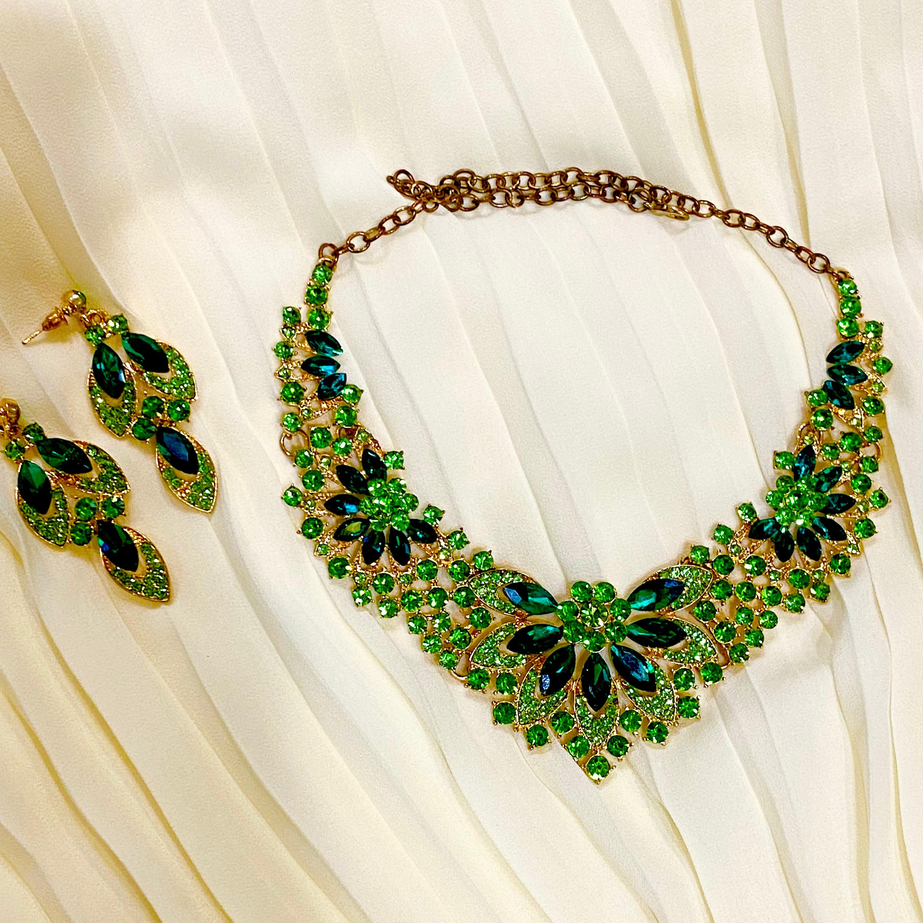 Green and gold necklace and earrings on a white fabric background
