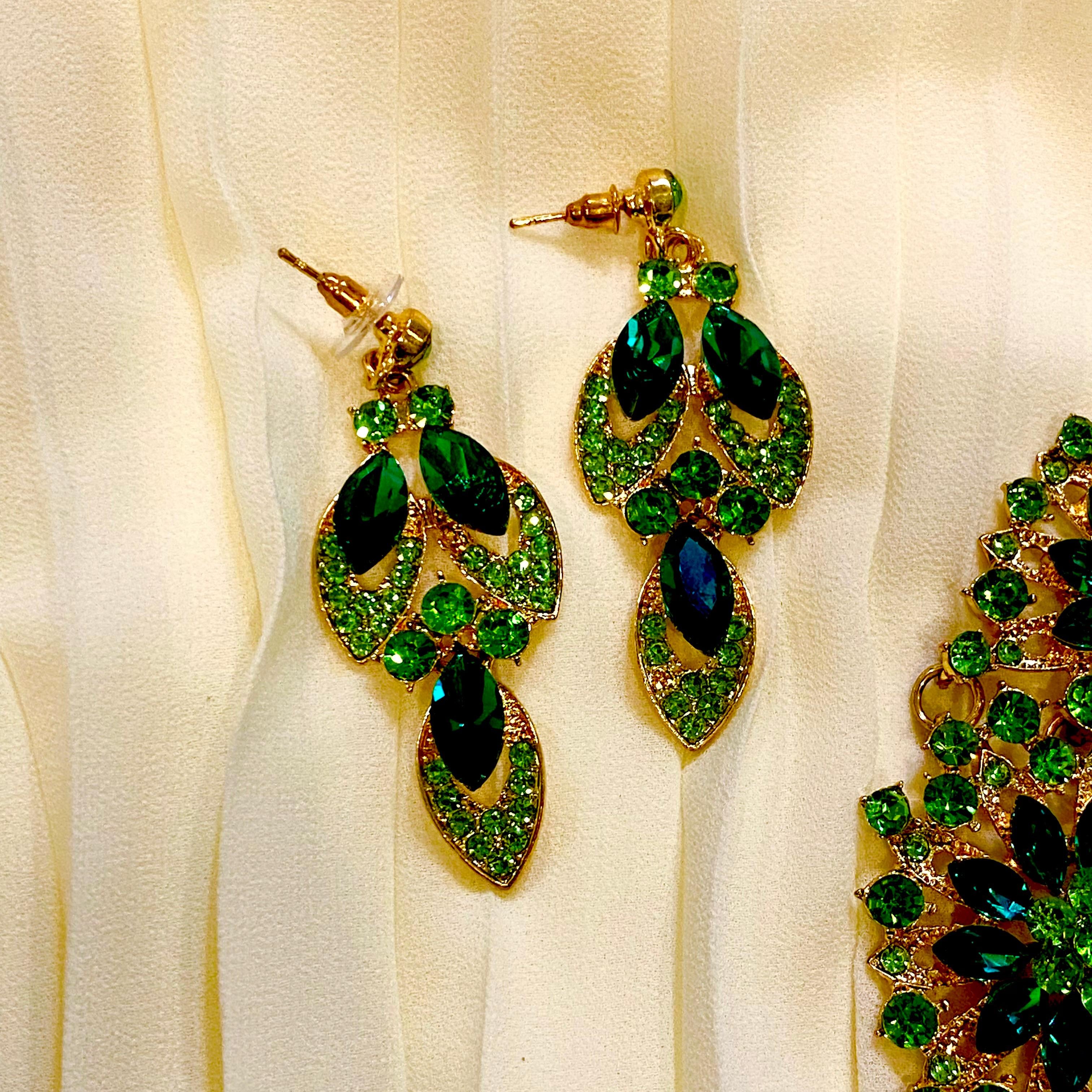 Green and gold earrings on a white fabric background