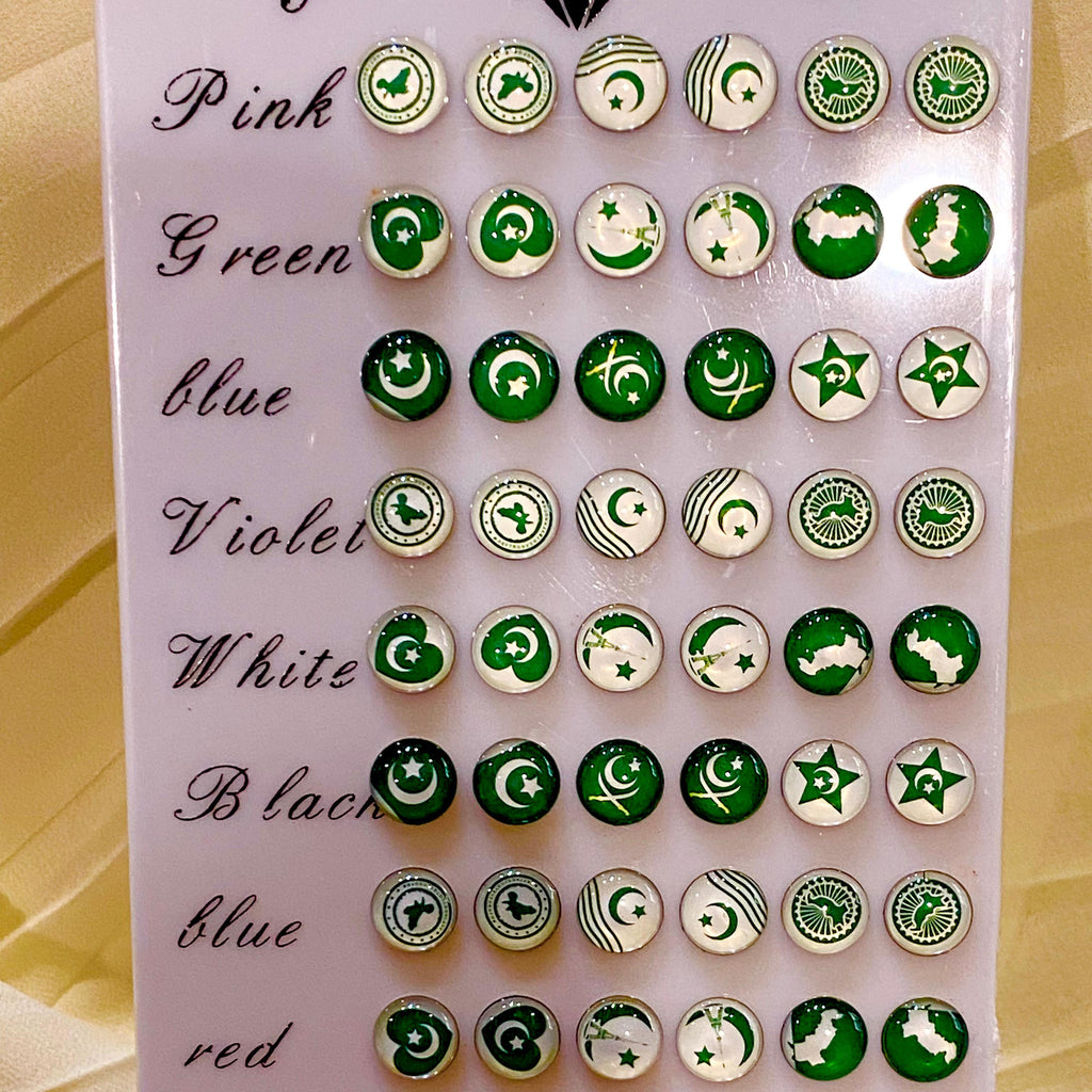 A display card showing multiple rows of round enamel pins in different colors, each row labeled with a color name like Pink, Green, blue, Violet, White, Black, red, and Plum. The pins feature green and white crescent and star designs, some with crescent moons and some with five-pointed stars.