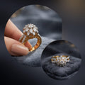 A gold ring with a diamond floral cluster setting, shown being held between fingers on a dark velvet surface, with two circular inset close-ups of the ring.