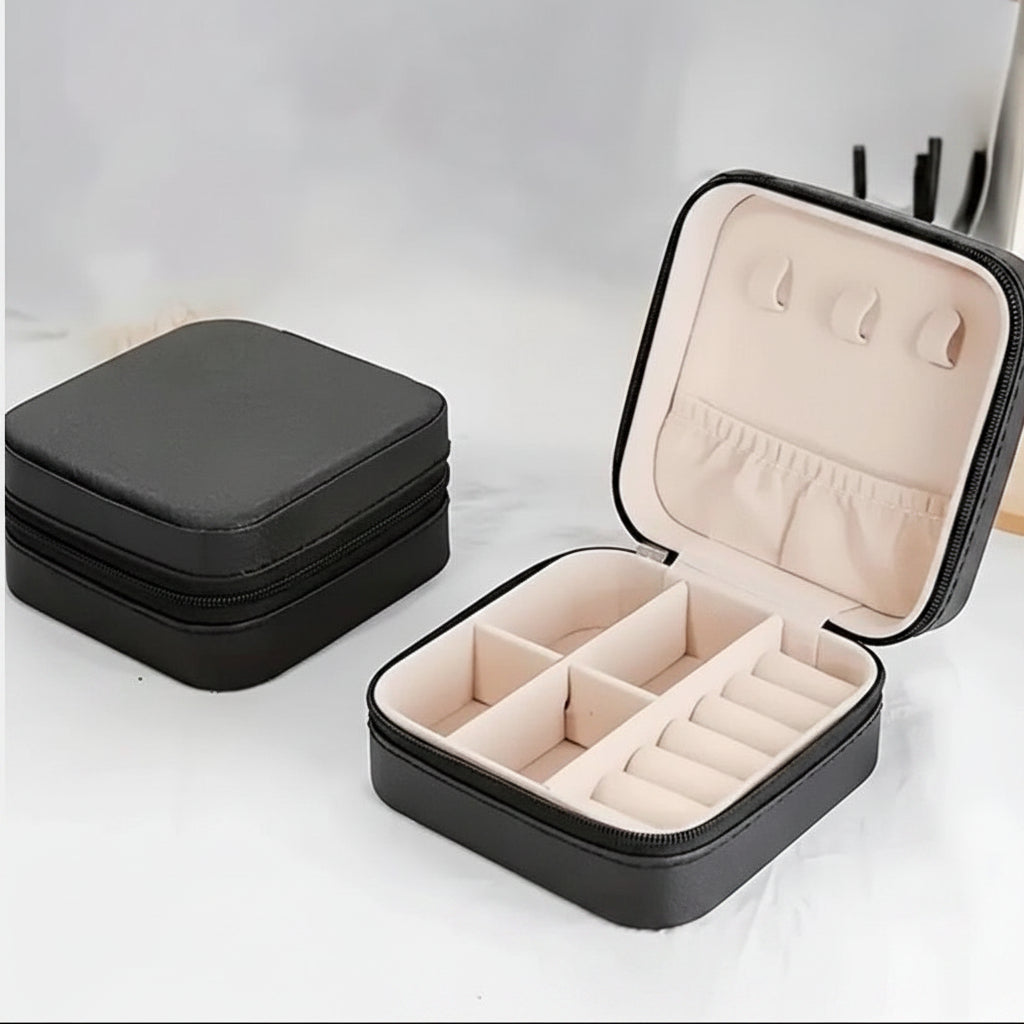 A black zippered jewelry organizer case shown closed on the left and open on the right, with a light beige interior featuring compartments, ring rolls, and ear hooks.