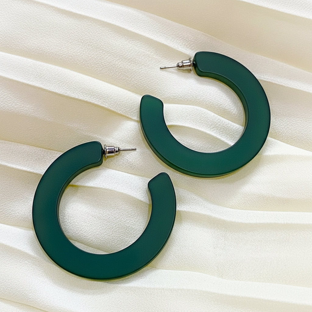 Green hoop earrings on a beige fabric background