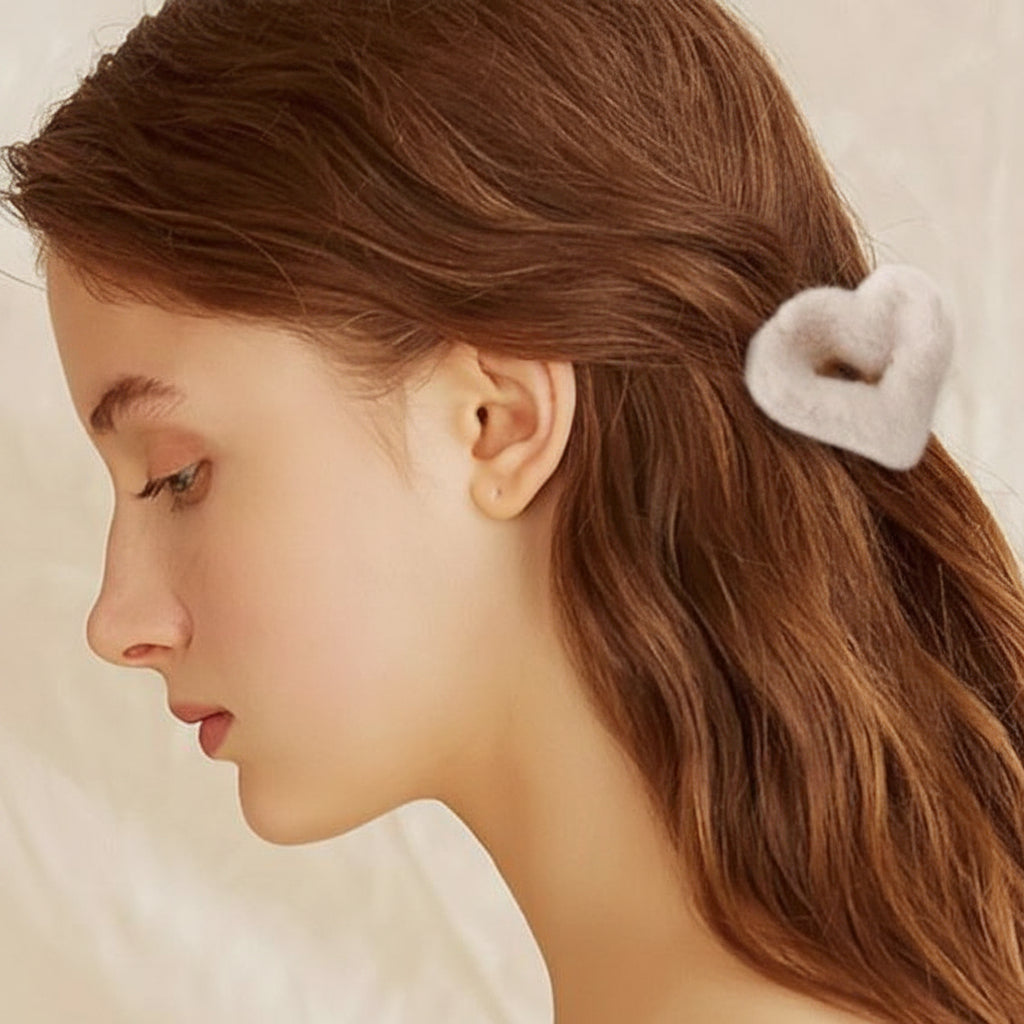 Woman with a heart-shaped hair clip in her brown hair against a neutral background