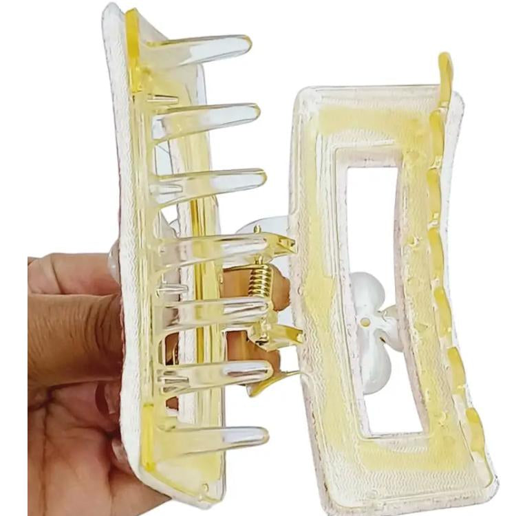 Clear hair clip with yellow interior held by a hand on a white background